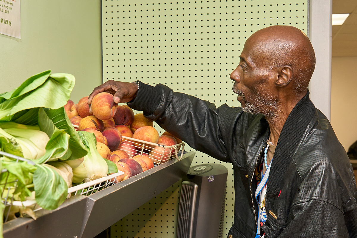 Client reaching for fresh produce in the William Temple House food pantry